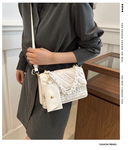 Close-up of white crossbody bag with embossed lettering and stylish chain strap