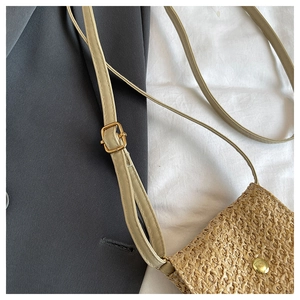 Close-up of straw woven crossbody bag with gold magnetic clasp and adjustable strap