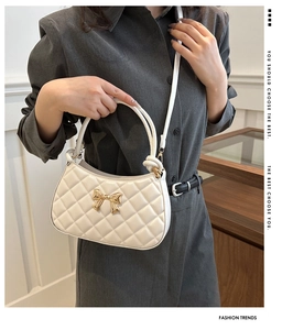 Détail d'un sac à main blanc matelassé avec un nœud doré et des finitions métalliques