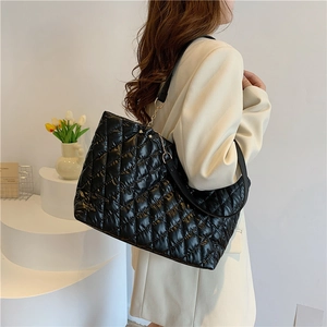 Minimalist black quilted tote bag with chain strap shown on a clean white display stand
