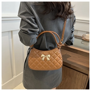 Détail du sac croissant marron matelassé avec fermoir nœud doré et poignée anneau