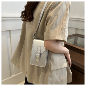 Detail of silver metallic leather phone bag with magnetic flap and slim strap on model