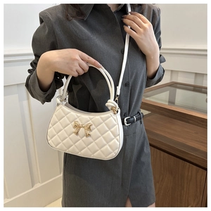 Détail du sac à bandoulière matelassé blanc avec boucle nœud dorée et coutures fines
