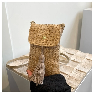 Detail of straw woven crossbody phone bag with fringe tassel and gold metallic snap button