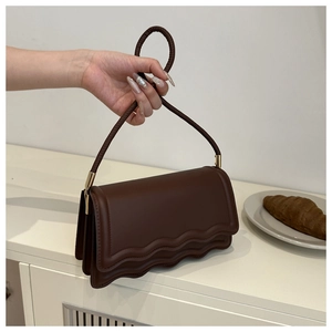 Detail of dark brown leather handbag with layered wave edges and twisted rope strap texture
