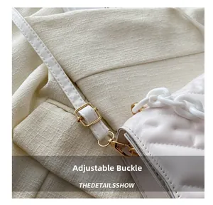 Detail of white quilted crossbody bag featuring gold metal buckle and chunky chain strap