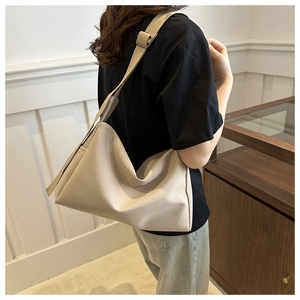 Detail view of a beige nylon crossbody bag with an adjustable wide strap on a model
