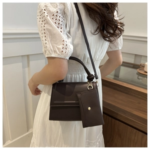 Detail of dark brown leather crossbody bag with knot handle and small hanging pouch