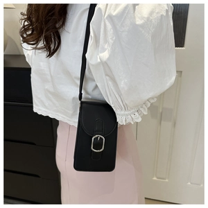 Detailed close-up of a black PU leather crossbody phone bag with silver buckle on a model