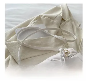 Detail of white quilted crossbody bag with chunky plastic chain and adjustable strap
