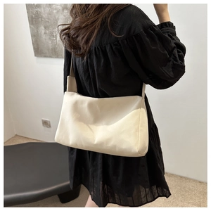 Minimalist beige nylon shoulder bag shown on model for size and capacity reference
