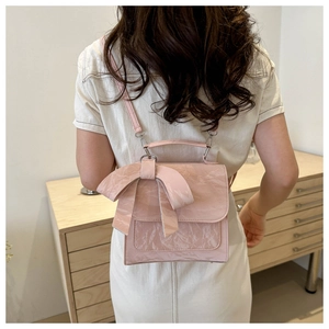 Pink bow backpack with wrinkled leather texture shown worn on a model's back