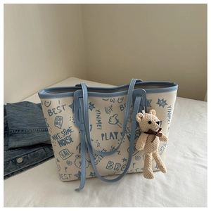 Detail of printed tote bag with blue graffiti, contrast trim and plush bear charm