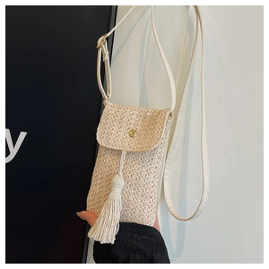 Detail of straw woven phone bag with golden magnetic clasp and long decorative tassels