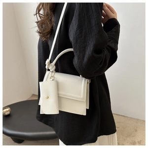 White minimalist crossbody bag with matching small coin purse pendant on shoulder strap
