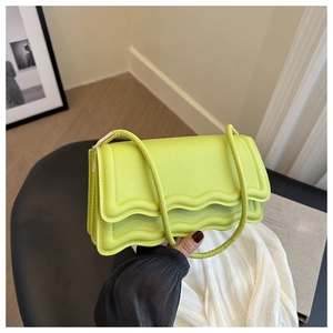 Dettaglio di una borsa a tracolla verde lime con patta ondulata e finitura in ecopelle
