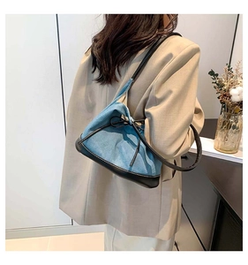 Detail view of denim contrast tote bag with bow accent worn by model in beige blazer