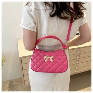 Détail d'un sac à main matelassé magenta avec nœud doré et poignée nouée élégante