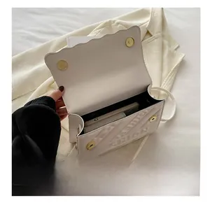 Detail view of white quilted crossbody bag with FASHION lettering and double magnetic closure