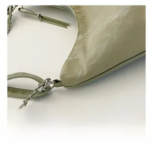 Détail du sac à bandoulière vert sauge en cuir marbré avec lacets et chaîne argentée
