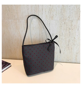 Close-up of heart print shoulder bag with black silk bow detail on stone background
