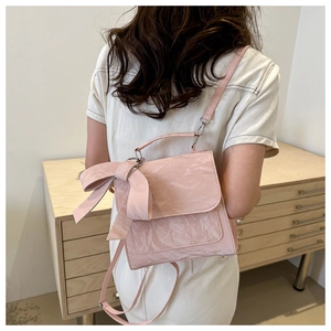Pink bow backpack with pleated texture and adjustable straps shown in lifestyle setting