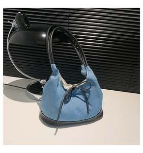 Detail of denim shoulder bag with black leather bow and premium leather handles
