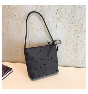 Detail of a charcoal tote bag with star patterns and a black ribbon bow on the shoulder strap