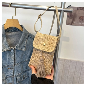 Detail of handmade woven straw crossbody bag with stylish long fringe and flip-top closure