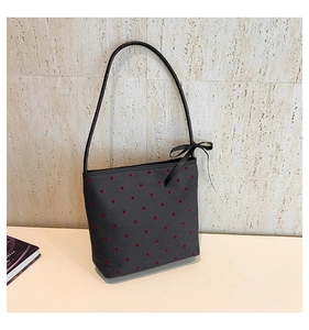Detail of red heart print on canvas tote bag with black ribbon bow and leather handles