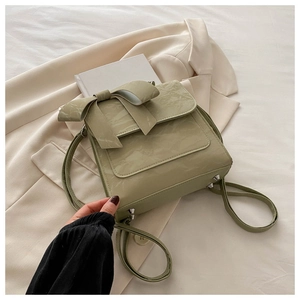 Detail of sage green pleated backpack with large bow decoration and metal rivets