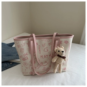 Detail of a large tote bag with pink graffiti prints and a cute teddy bear charm