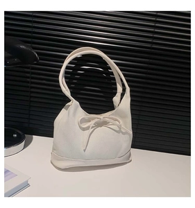 Close-up of cream canvas tote bag featuring delicate bow decoration and leather reinforced base