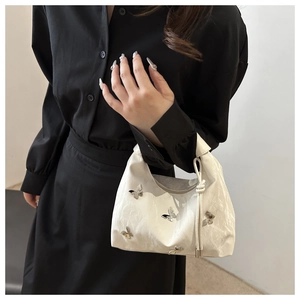 Sac fourre-tout blanc avec pendentif papillon argenté et texture plissée élégante
