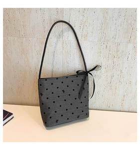 Detail of grey polka dot fabric bag with small bows and black ribbon accent