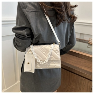 White quilted crossbody bag with embossed letters, thick chain, and small pouch detail