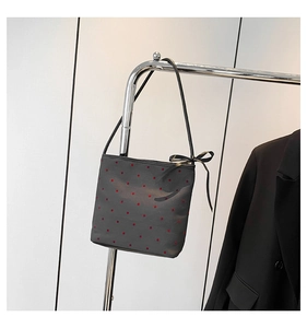 Detail of black shoulder bag with red polka dots and decorative silk bow on the zipper