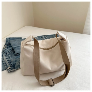 Close-up of beige nylon tote bag showing metallic zipper and brown wide strap details