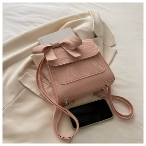 Pink faux leather crossbody bag with pleated texture and large bow detail