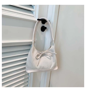 Close-up of cream herringbone fabric tote bag with elegant bow detail on white shutters