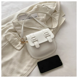 Detail of white matte leather saddle bag featuring gold hardware and adjustable strap