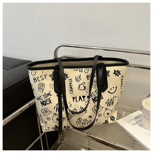 Dettaglio della borsa tote graffiti con stampe nere audaci su materiale bianco sporco