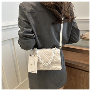 Close-up of a white quilted shoulder bag with resin chain and FASHION embossed detail