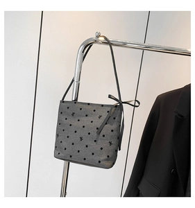Close-up of grey tote bag with heart pattern, bow embroidery, and long black handles