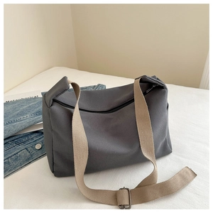 Detailed view of dark grey nylon crossbody bag with adjustable khaki shoulder strap on fabric