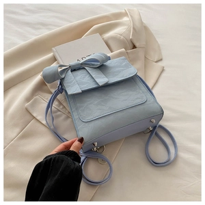 Detail view of light blue backpack featuring bow decoration and silver metal base studs