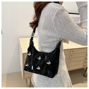 Détail du sac plissé noir avec cinq ornements métalliques en forme de papillon argenté
