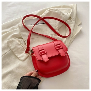 Detail of red PU leather saddle bag with flap buckle closure on beige fabric background