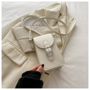 Close-up of cream PU leather crossbody phone bag with matte silver buckle on a blazer