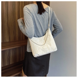 Détail du sac à main blanc plissé avec bandoulière en chaîne argentée sur modèle